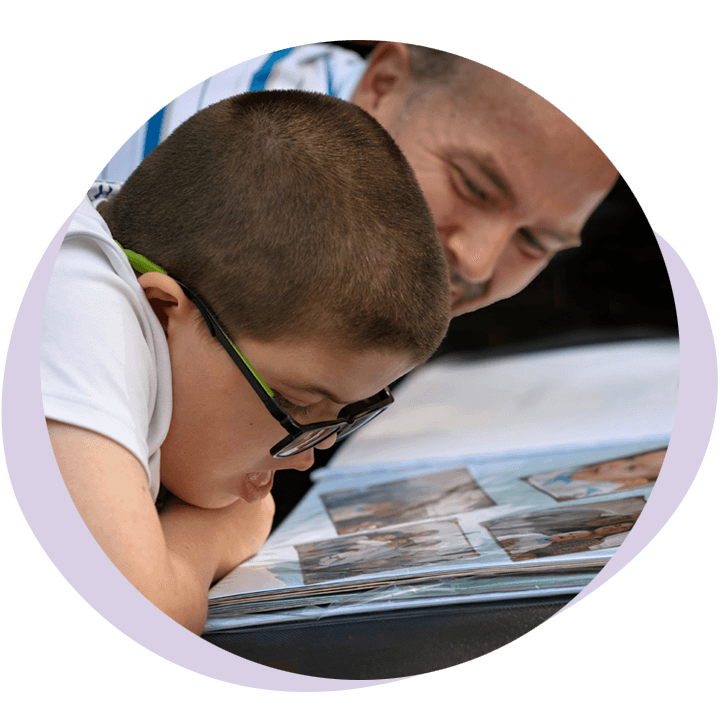 Un enfant qui regarde un album photo avec son papa-L'Accompagnateur